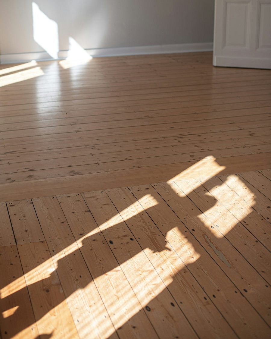 Leerer Raum mit frisch abgeschliffenem Dielenboden, Sonnenlicht fällt in Streifen über das Holz